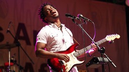Blick Bassy auf der Bühne mit einer Gitarre