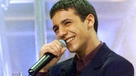 Faudel lächelt mit Mikrophon in der Hand