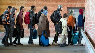 Flüchtlinge, die zuvor mit einem Sonderzug angekommen waren, warten am 03.10.2015 am Bahnhof in Schönefeld (Brandenburg), auf ihre Weiterfahrt zur Unterkunft mit Bussen
