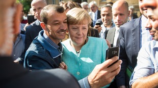  Bundeskanzlerin Angela Merkel (CDU) lässt sich am 10.09.2015 nach dem Besuch einer Erstaufnahmeeinrichtung für Asylbewerber der Arbeiterwohlfahrt (AWO) und der Außenstelle des Bundesamtes für Migration und Flüchtlinge in Berlin-Spandau für ein Selfie zusammen mit einem Flüchtling fotografieren