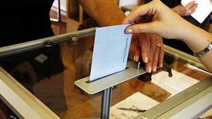 Eine Frau wirft einen Stimmzettel in die Urne