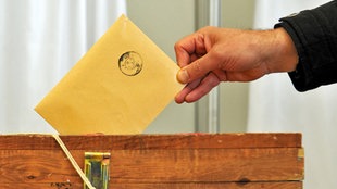 Ein Mann wirft einen Wahlzettel in die Urne