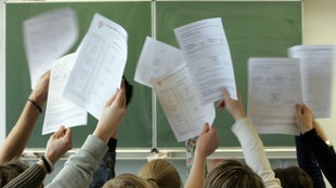 Schüler halten Zeugnisse in die Luft