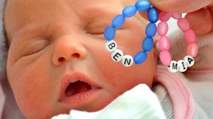 ILLUSTRATION - Namens-Armbänder "Ben" und "Mia" werden auf der Mutter-Kind-Station vor ein zwei Tage altes Baby gehalten