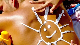 Eine Sonne aus Sonnenmilch hat eine junge Frau auf den Rücken ihres Freundes gemalt