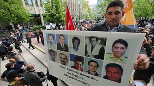 Ein Mann steht mit Bildern der NSU-Opfer am 06.05.2013 vor dem Gericht in München (Bayern)