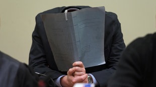 Der Angeklagte Holger G. verbirgt am 12.06.2013 im Gerichtssaal in München (Bayern) sein Gesicht hinter einem Aktenordner
