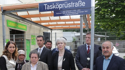 Staatsministerin Aydan Özuguz(SPD, l-r), Verwandte der Familie Tasköprü, der Bundesvorsitzende von Bündnis90/Die Grünen, Cem Özdemir, Hamburgs Kultursenatorin Barbara Kisseler (l-r), der Vorsitzende der Bezirksversammlung Altona, Frank Toussaint und der Vater des NSU-Opfers, Süleyman Tasköprü, Ali Tasköprü, stehen am 26.06.2014 in Hamburg unter dem Strassenschild der "Tasköprüstrasse"