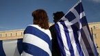 Griechischer Mann und Frau mit Fahnen vor Parlament in Athen