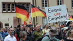 Pegida Demonstration mit Fahnen und einem Platkat