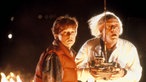 Marty McFly und Doc Brown blicken erstaunt, hinter ihnen brennt der Boden