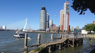 Blick auf die Skyline von Rotterdam mit Ersamus-Brücke und zwischen den Hochäusern das Hotel America, von wo die Wohlhabenden Richtung Amerika auswanderten